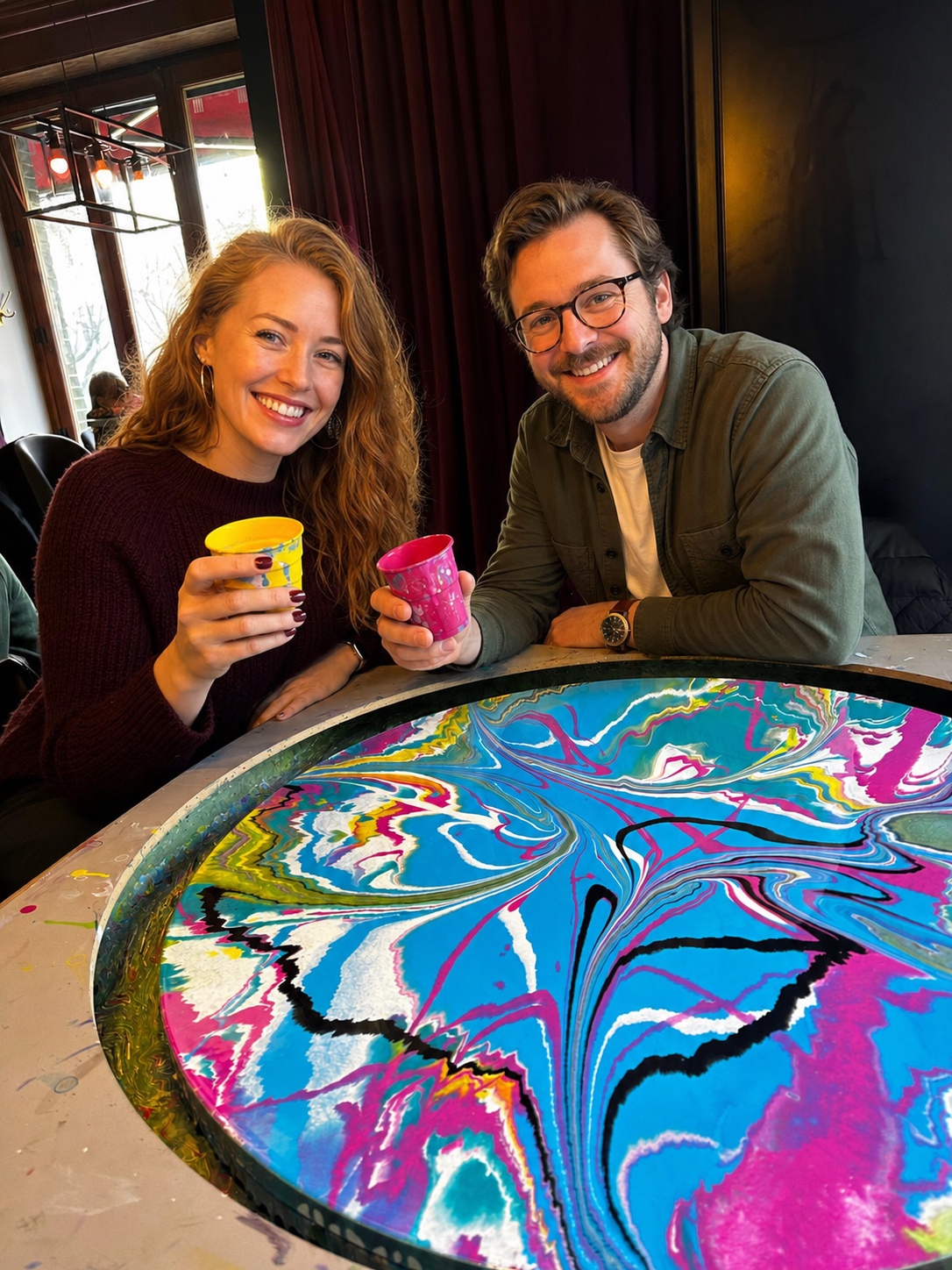 Paar mit Farbbechern und fertigem Kunstwerk beim Brunch & Art Workshop