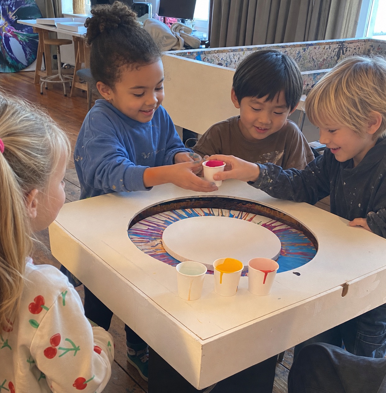 Kinder beobachten ein farbiges Spin Painting an der kleinen Kunstmaschine