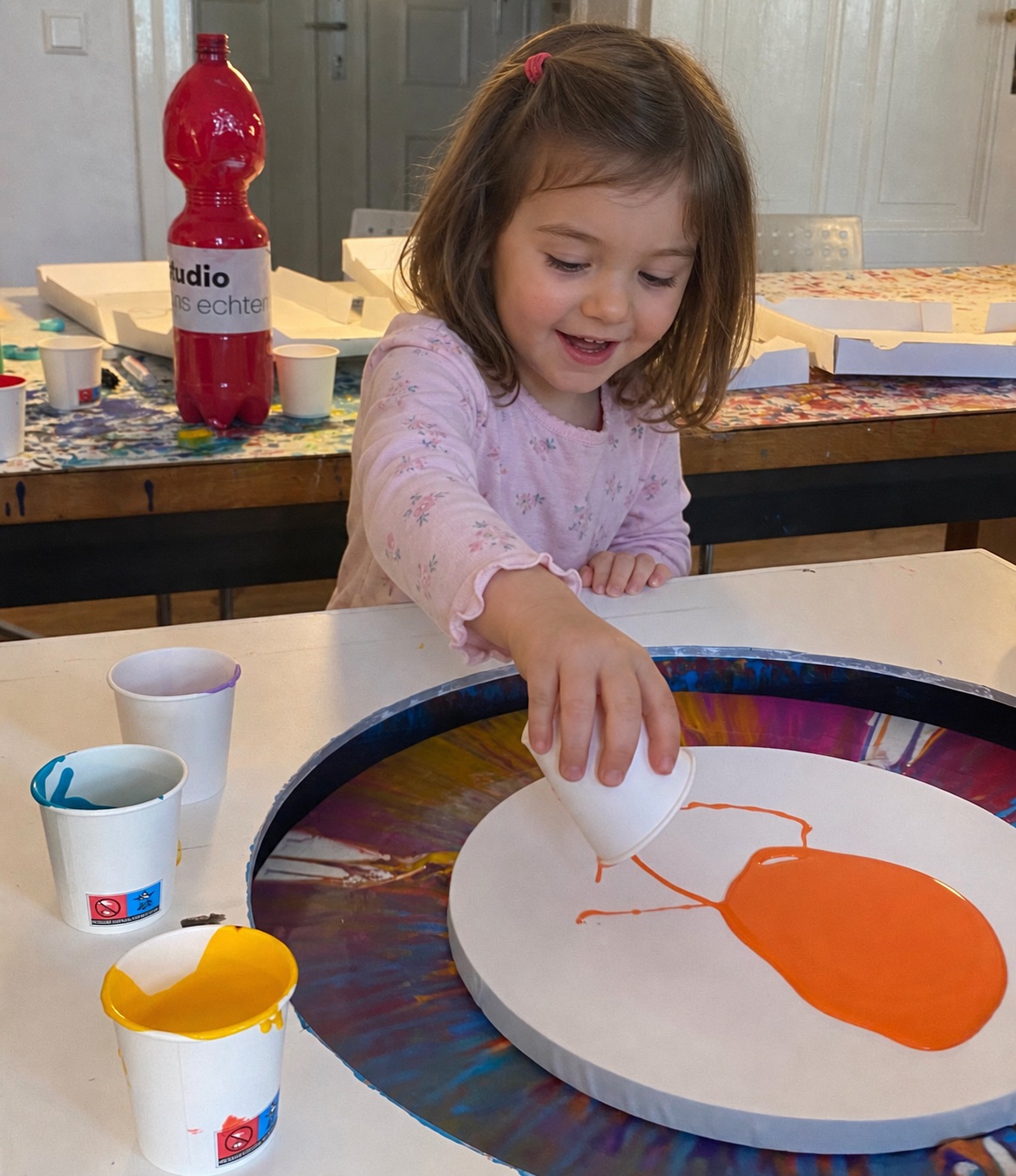 Kind gibt Farbe auf eine runde Leinwand der kleinen Spin-Art-Maschine