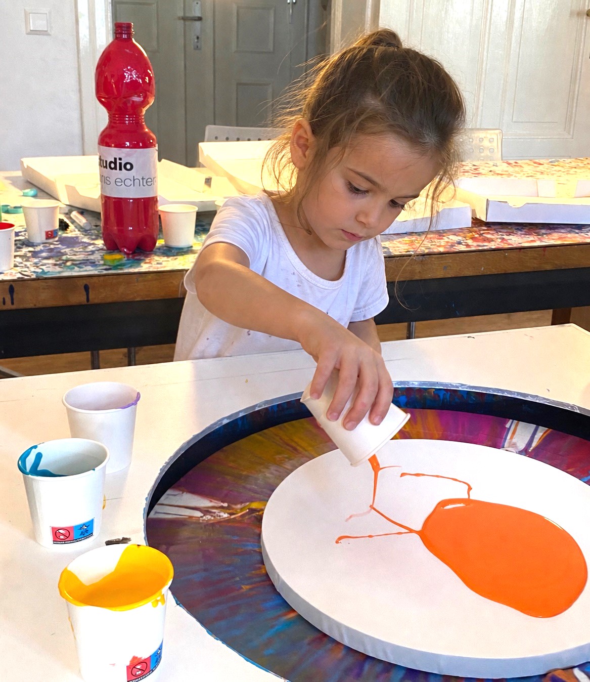 Kind gibt orange Farbe auf eine runde Leinwand