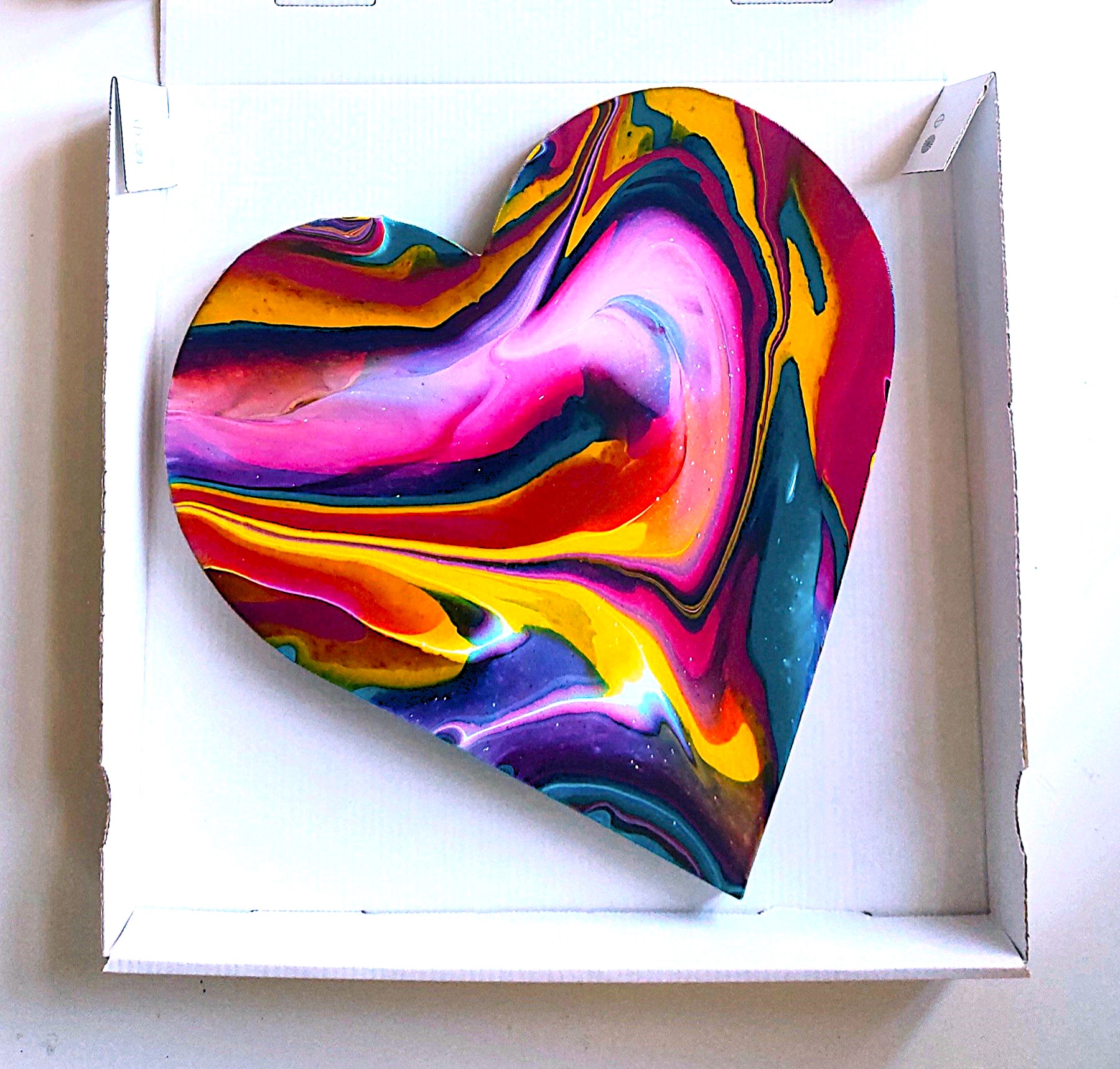 Colourful heart-shaped spin painting in a white transport box