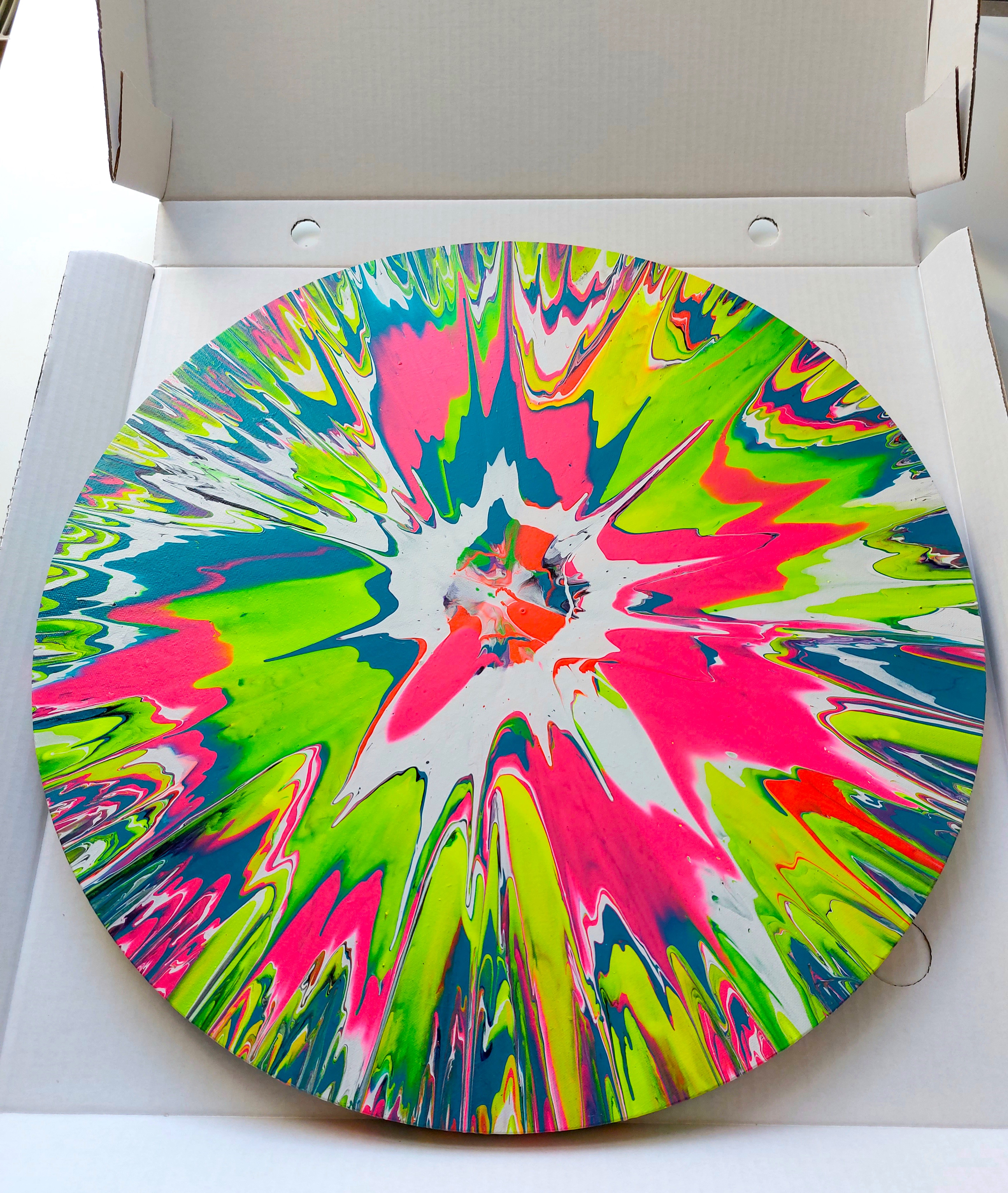 Vibrant round spin painting in an open white transport box