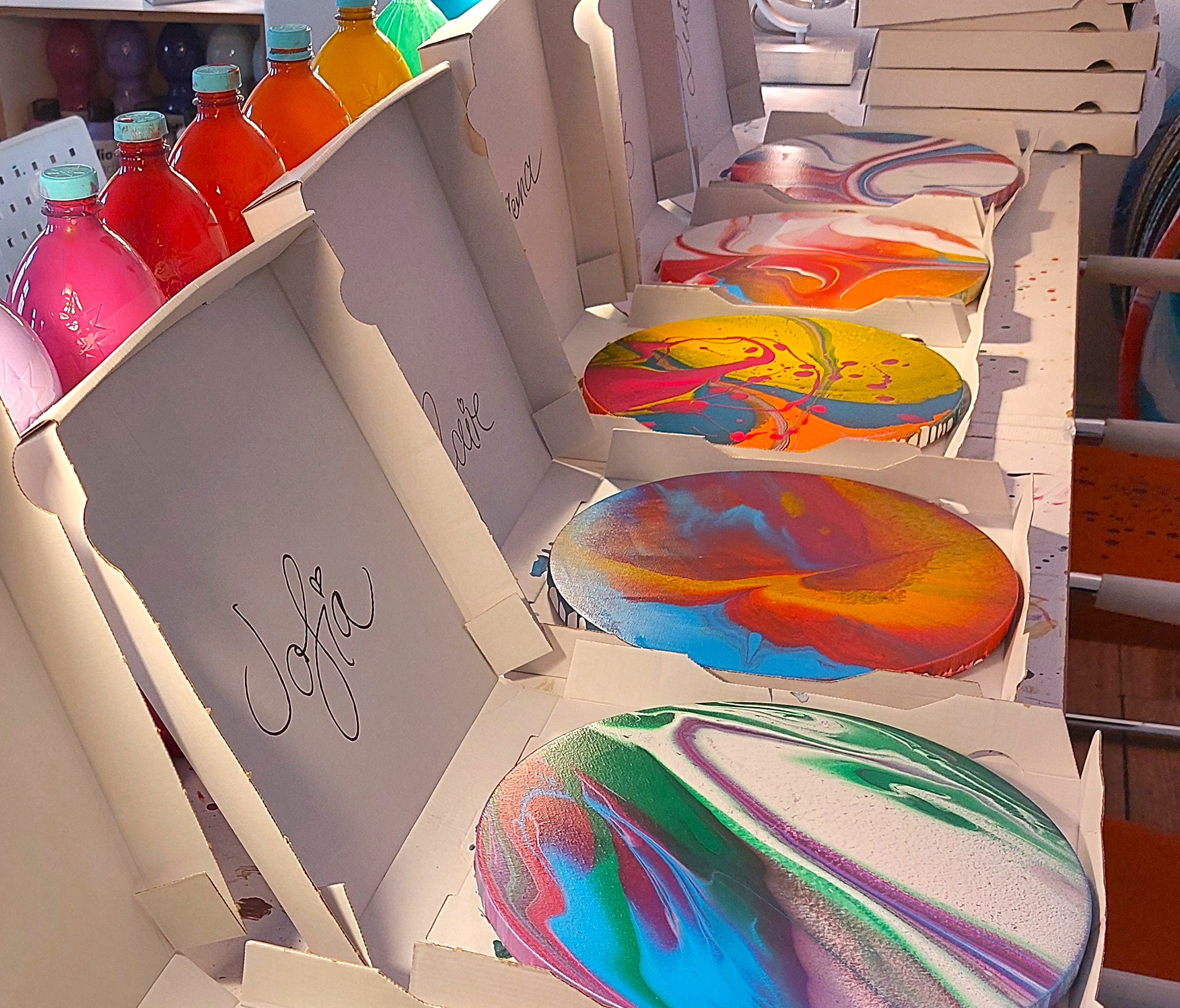 Several round spin paintings in white transport boxes