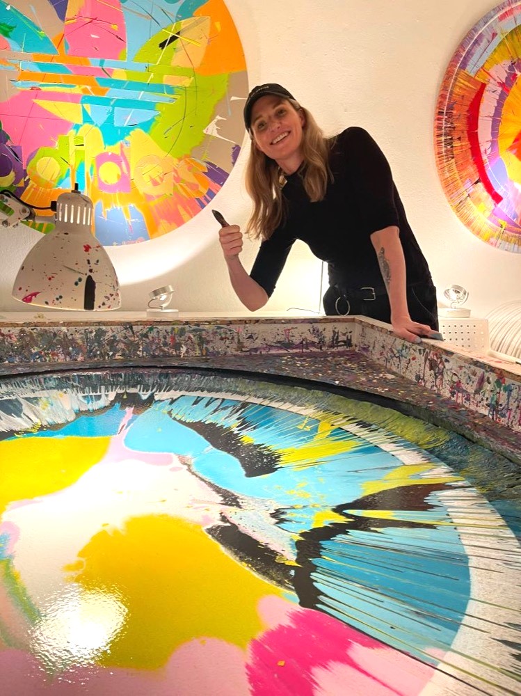 Teilnehmerin hinter einem farbenfrohen Spin Painting im Studio