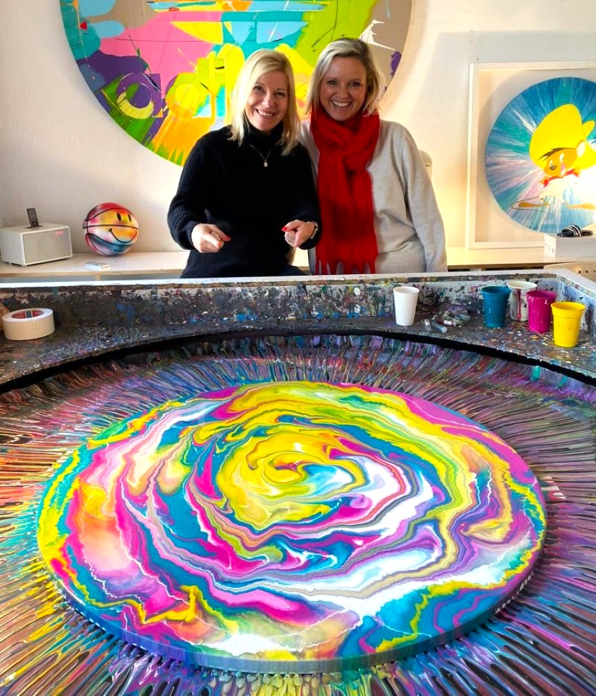 Zwei Teilnehmerinnen hinter ihrem farbenfrohen Spin Painting