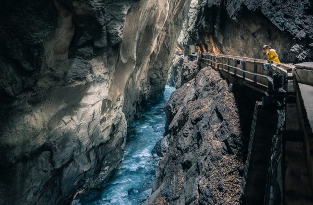 Taminaschlucht mit türkisem Fluss und Holzsteg an der Felswand